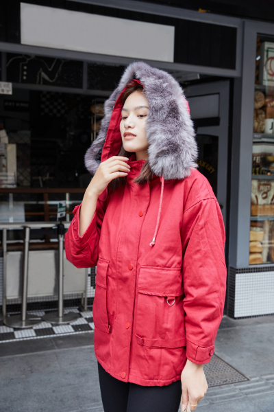 服饰系列实景模特穿着带毛领的红色羽绒棉服毛衣和黑色长裤的街头摆拍