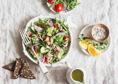 Tuna, arugula, tomato, cucumber salad with mustard dressing. Healthy diet food. Mediterranean style. On a light background, top view