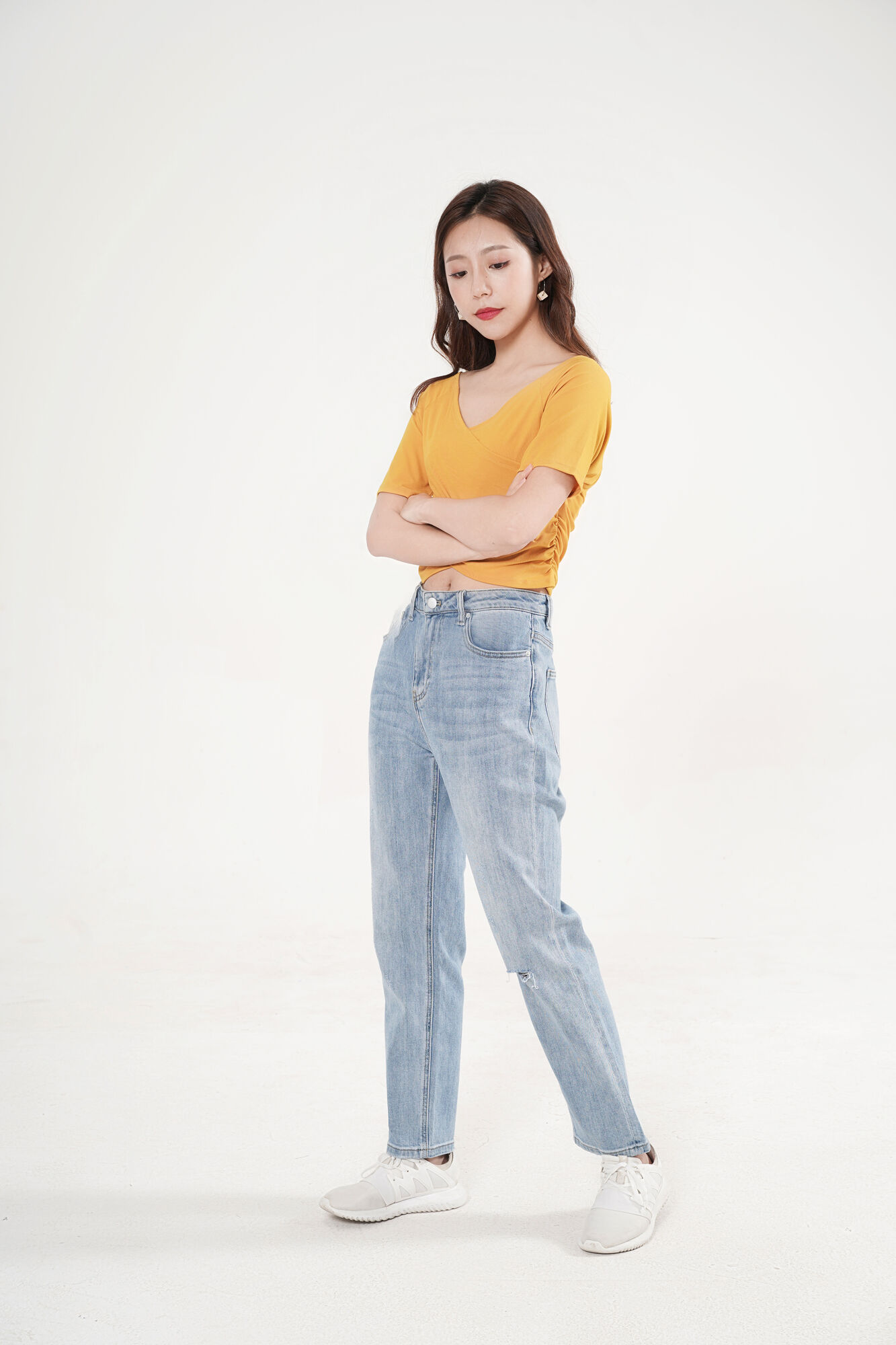 服饰系列写实模特穿着姜黄色V领短袖上衣和蓝色牛仔长裤的摆拍
