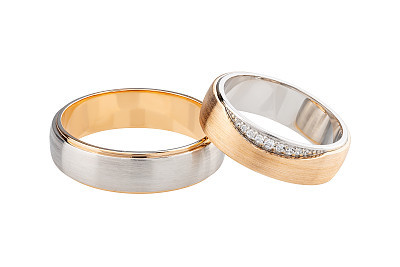 Pair of wedding silver ring and pink gold ring decorated with diamonds isolated on white background