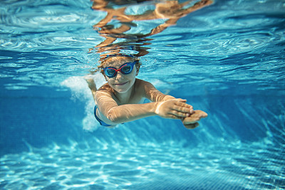 Little boy swimming underwater in pool
