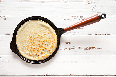 Cast iron pancake skillet on old white wooden table