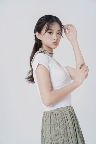 服饰系列实景模特穿着白色交襟短袖上衣和豆绿色百褶半裙