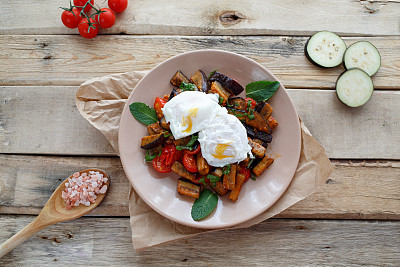 Poached eggs with baked vegetables on the wooden table homemade. Top view.