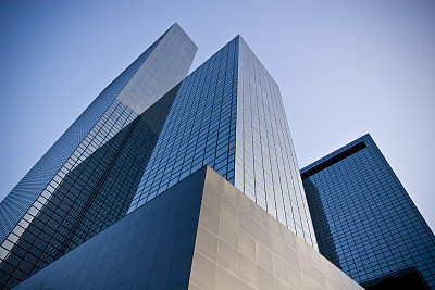 Bottoms up view of three skyscrapers and a blue sky