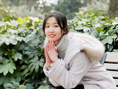 Portrait of beautiful young brunette woman in white winter fluffy coat. Outdoor fashion glamour Chinese teenage stylish lady. Emotions, people, beauty and lifestyle concept.