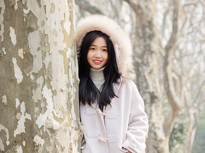 Portrait of beautiful young brunette woman in white winter fluffy coat. Outdoor fashion glamour Chinese teenage stylish lady. Emotions, people, beauty and lifestyle concept.