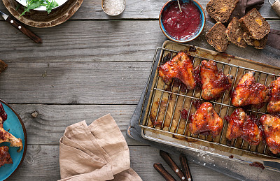 Chicken wings in cranberry sauce on rustic wooden table with copy space, top view