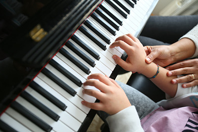 A music teacher is teaching her student how to play the piano.