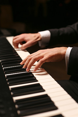 Hands on piano. The pianist plays the piano. Piano keys on black background