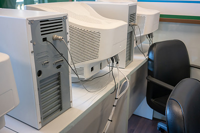 old CRT computer monitors and towers in classroom.