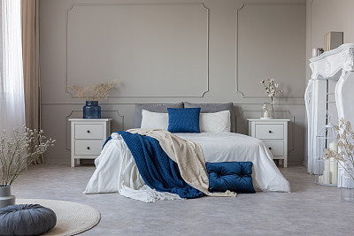 White fireplace portal, two nightstand with drawers and king size bed with petrol blue and white bedding