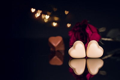 Red rose and heart shaped chocolate on black background