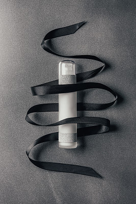 view from above of lotion and black ribbon on silver