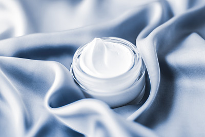 Beauty face cream jar on a soft blue silk