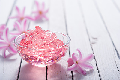 Cosmetic cream, moisturizer gel, pink flower, white wooden table