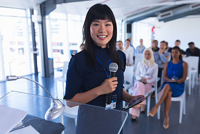 Female speaker with digital tablet speaks in business seminar