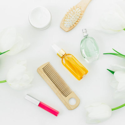 Cosmetics, perfume, styling tools and tulips flowers on white background. Beauty blog composition. Flat lay, top view