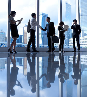 Five business people in a hallway by glass windows