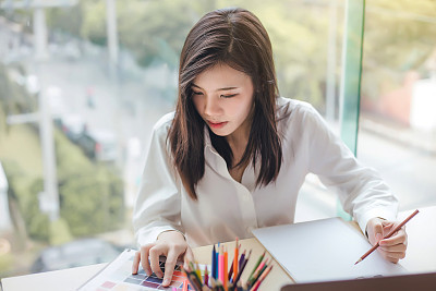Young woman graphic designer working on laptop and computer in the office