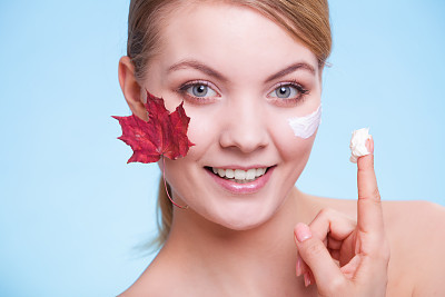 Skin care. Face of young woman girl with red leaf.