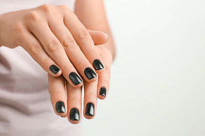 Woman with stylish black manicure on white background, closeup
