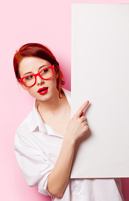 photo of beautiful young woman holding empty poster on the wonderful pink studio background