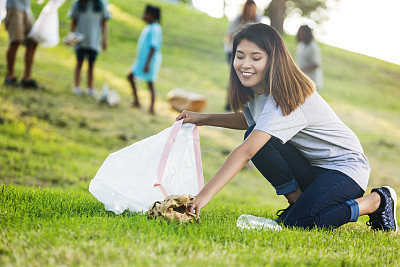 Happy young woman pick up trash in the park