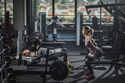 Young athletic couple having body building training in a gym.