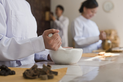 Traditional Chinese doctors mixing medicine ingredients