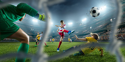 Soccer kids players scoring a goal. Goalkeeper tries to hit the ball