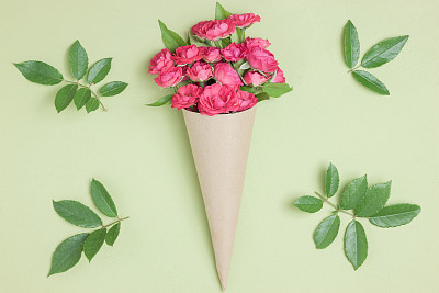 Bouquet of small red roses in vintage paper on the table.