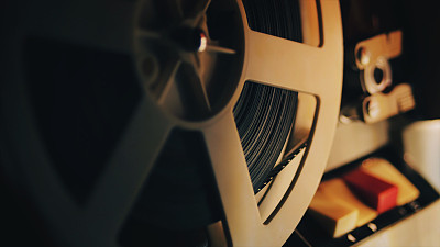 Old 8mm film projector playing in the night. Close-up of a reel with a film