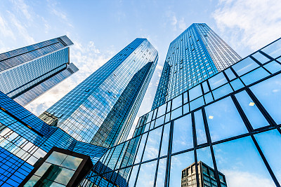 Bottom view of modern skyscrapers in business district against blue sky with clouds
