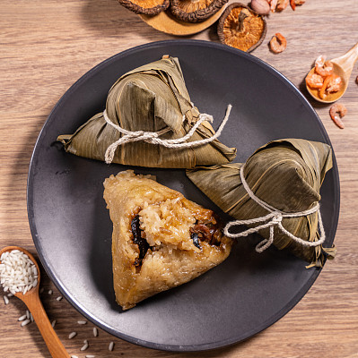 Zongzi, steamed rice dumplings on wooden table bamboo leaves, food in dragon boat festival duanwu concept, close up, copy space, top view, flat lay