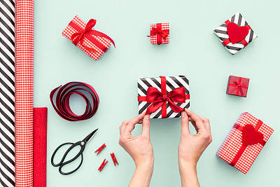 Close up on female hands packing presents. Top view.