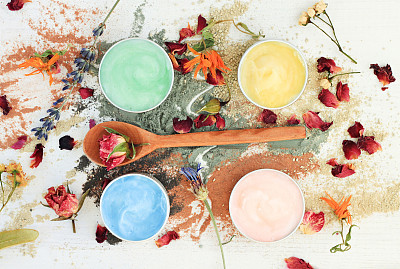 different clay facial masks in jars, powder and dried herbs
