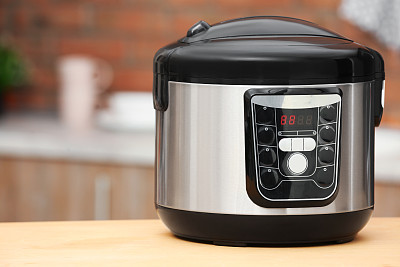 Modern electric multi cooker on table in kitchen. Space for text