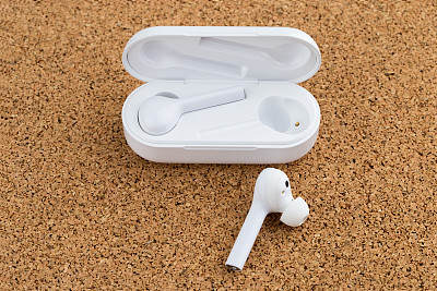 Wireless headphones on cork surface. Wireless headset in a case for charging close-up.