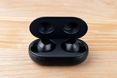 Wireless headphones on a wooden background. Headset close up in the charging case close-up.