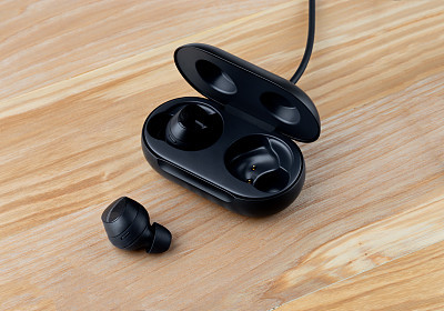 Wireless headphones on a wooden background. Headset close up in the charging case close-up.