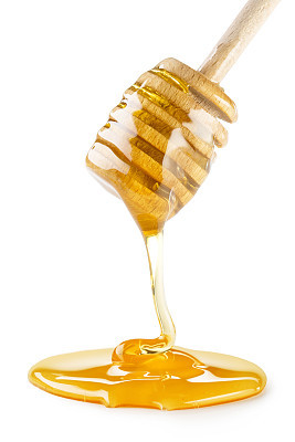 honey dripping from a wooden dipper
