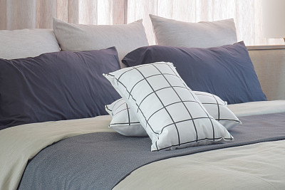 Black and white pillows setting on dark gray bed runner in the bedroom
