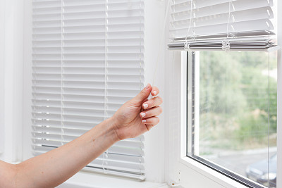 Adjusting the white blinds in height use a cord