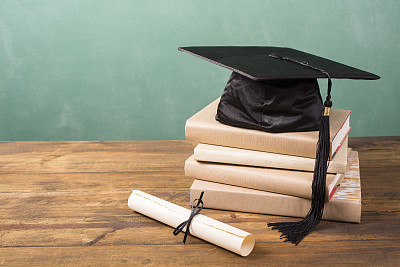 Graduation!  Cap, motarboard and tassel with dilploma on desk. Education.