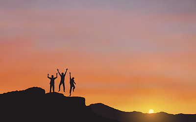 Silhouette of happy men jumping on Mountain cliff looking at sunrise sky background
