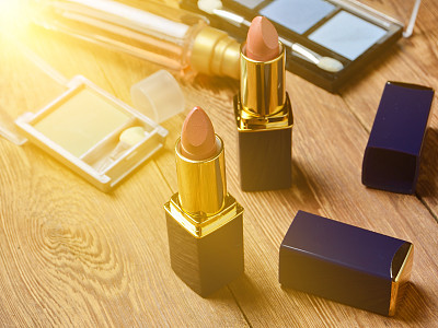 Women's lipstick and make-up cosmetics on a wooden table.