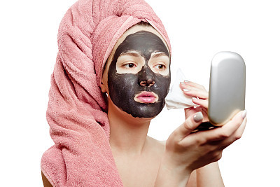 Pretty sexy woman with black face mask wipes black mask from face with napkin