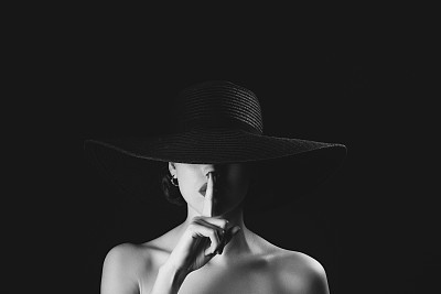 Monochrome studio shot of young beautiful woman wearing hat
