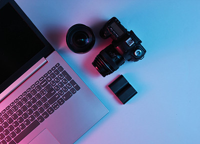 Equipment professional photographer. Laptop, camera, lenses. Neon light. Top view
